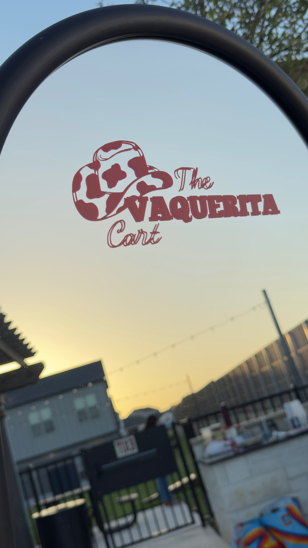 The Vaquerita Cart logo on a mirror at golden hour