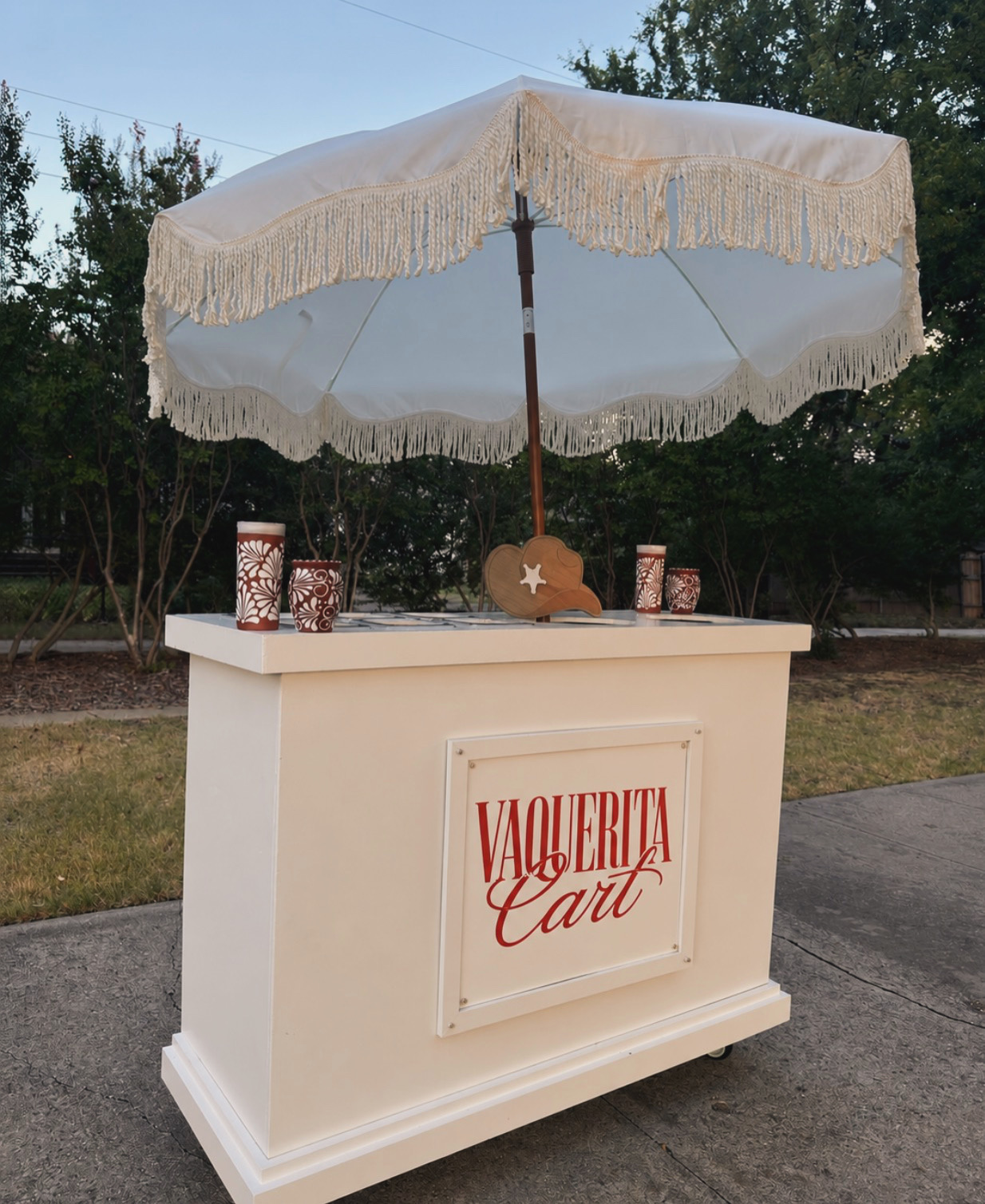 Vaquerita Cart set up outdoors with fringed umbrella and elote cups